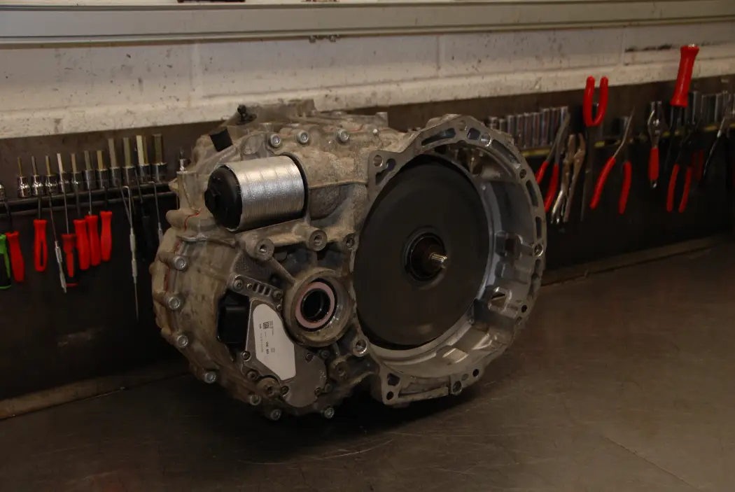 An automatic gearbox placed on a workshop bench ready for inspection and rebuild, with various tools and equipment neatly arranged on the wall behind it.